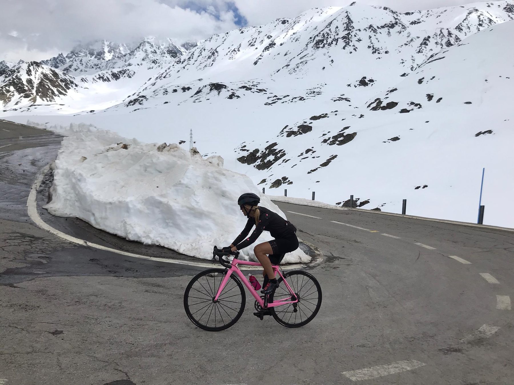 Cycliste seule sur une route de col alpin encore enneigée au printemps
